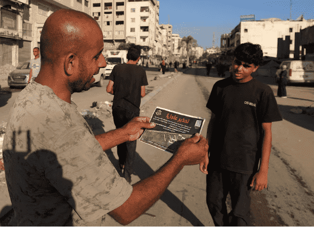 Un homme palestinien tient un tract, largué par les forces israéliennes, ordonnant aux habitants de la ville de Gaza d’évacuer, à Gaza, le 9 septembre 2025.